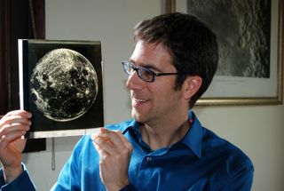 Dean Regas, an astronomer at the Cincinnati Observatory in Ohio and author of the book "Facts from Space!" holds a slide with a photo of the moon.