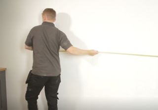 man measuring a white wall
