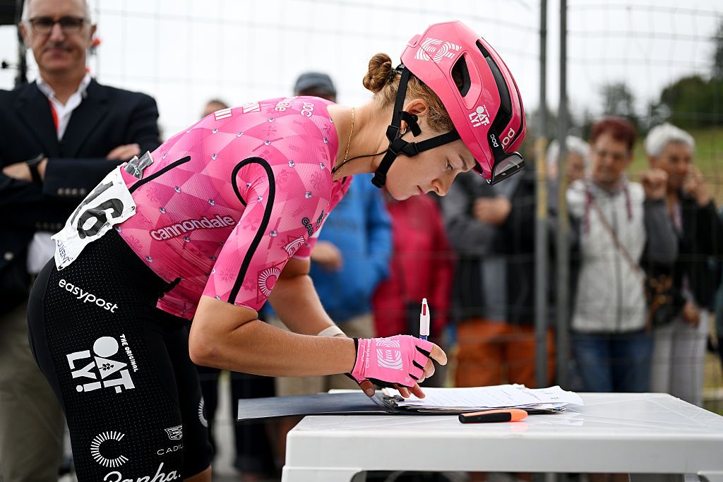 Veronica Ewers signs something on a table dressed in pink