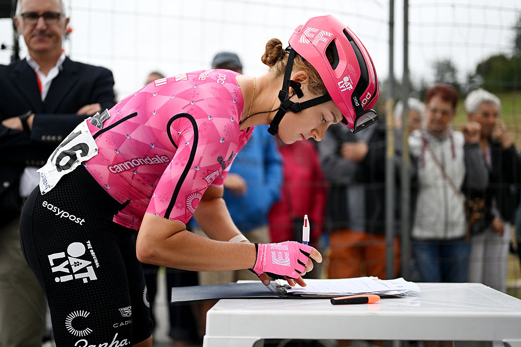 Veronica Ewers signs something on a table dressed in pink