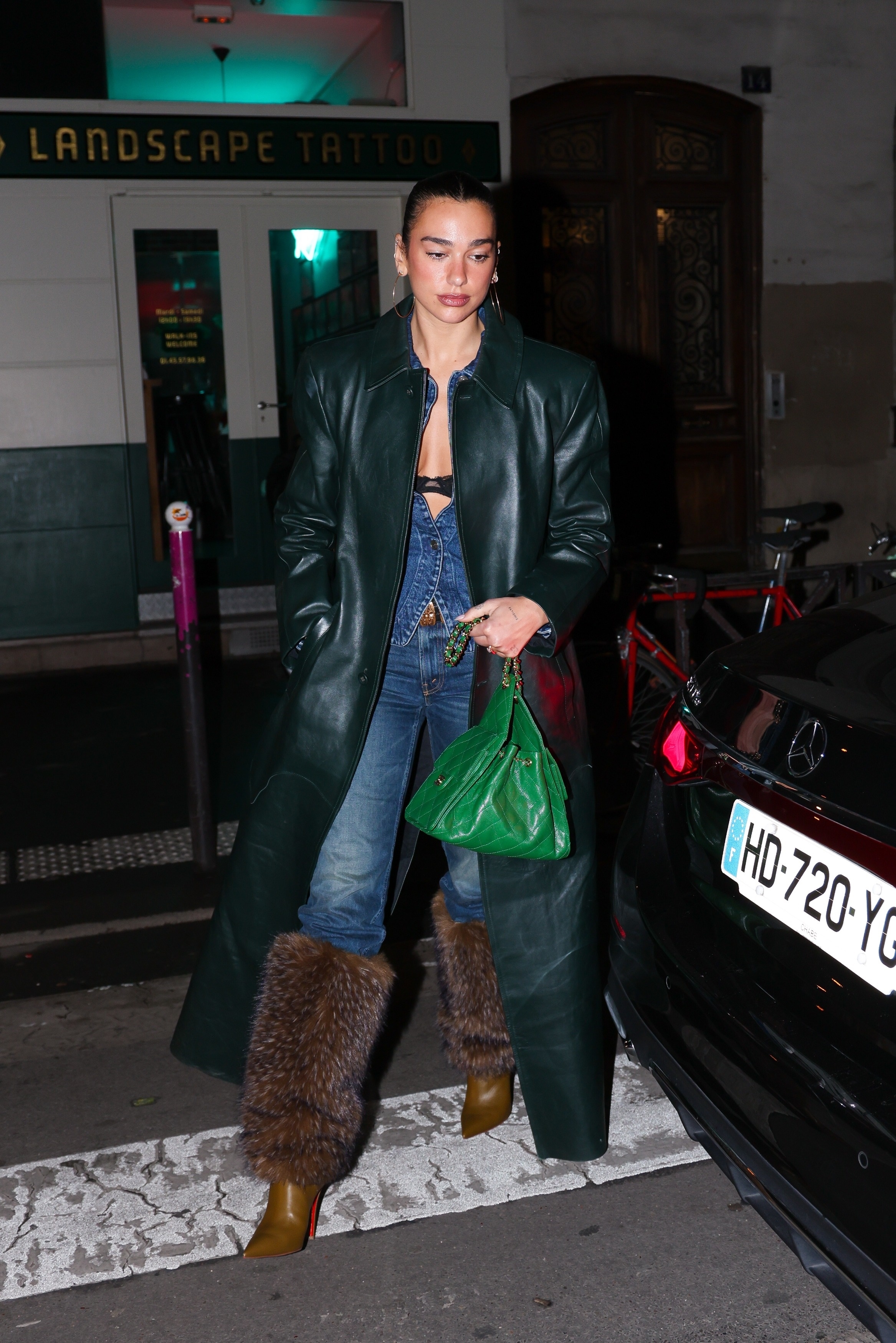 Dua Lipa was spotted in Paris wearing a dark green leather coat, skinny jeans, boots with fur, and a Chanel 25 bag