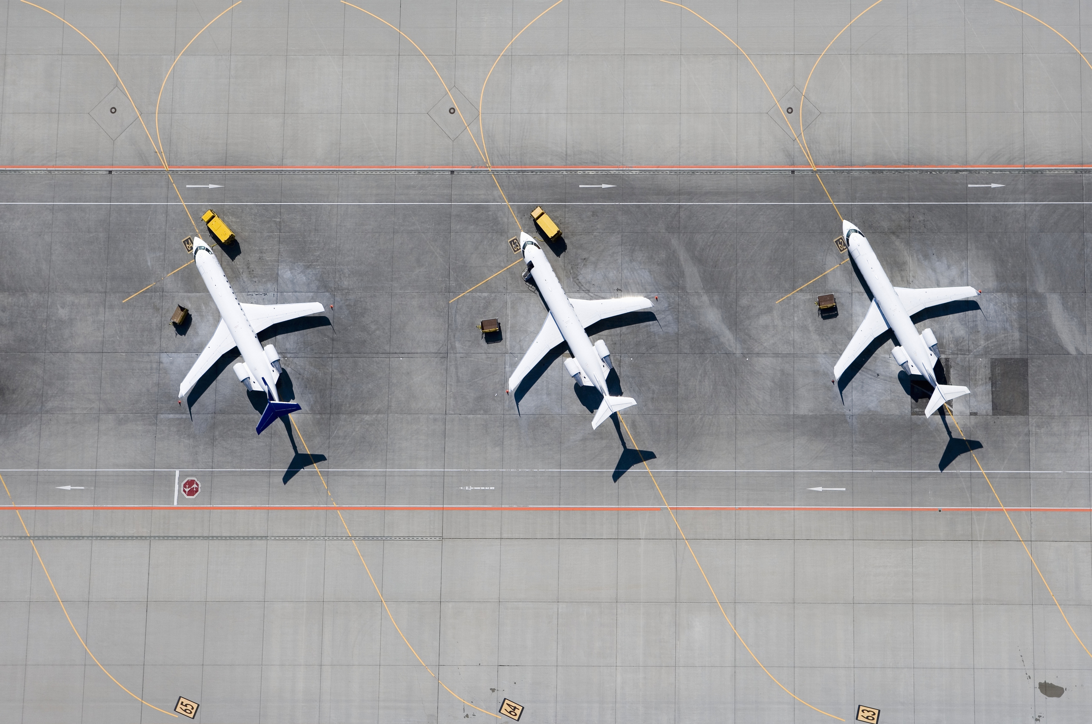 Three airplanes in a row, seen from above, on a runway.