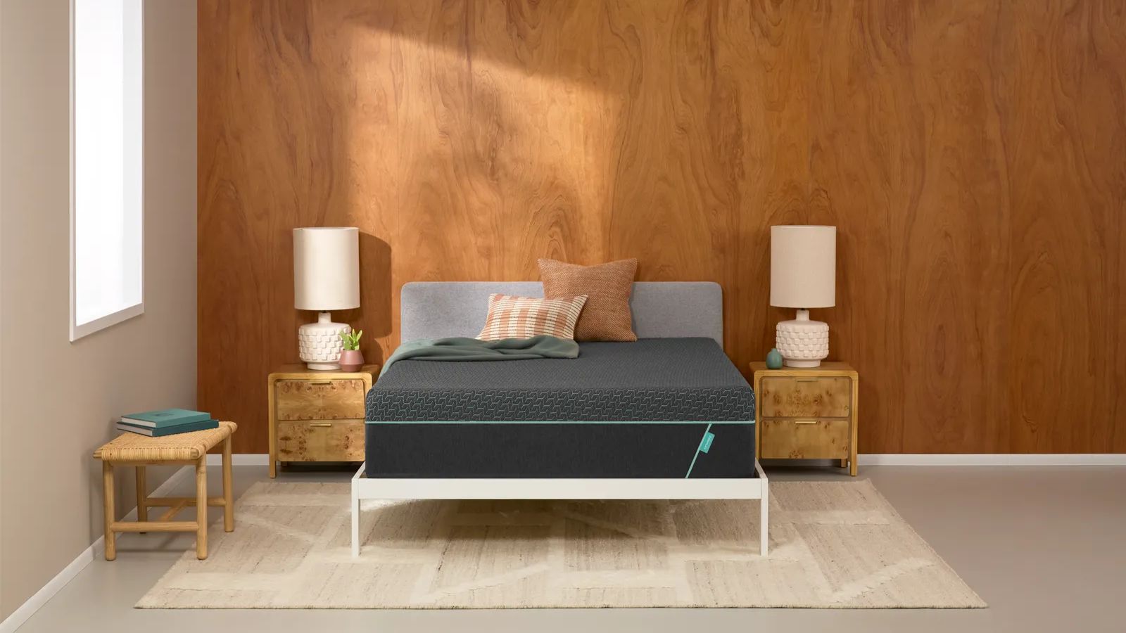 Bedroom with wooden walls, bed with two wooden bedside table, cream rug, window to the left of the wall