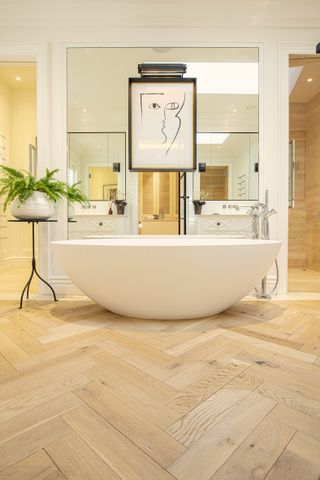 bathroom with freestanding bath and herringbone engineered wood flooring