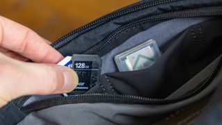 Three small stretchy pockets on the inside lid of the Bellroy Venture 10L Sling Camera Edition bag packed with memory cards and a spare battery