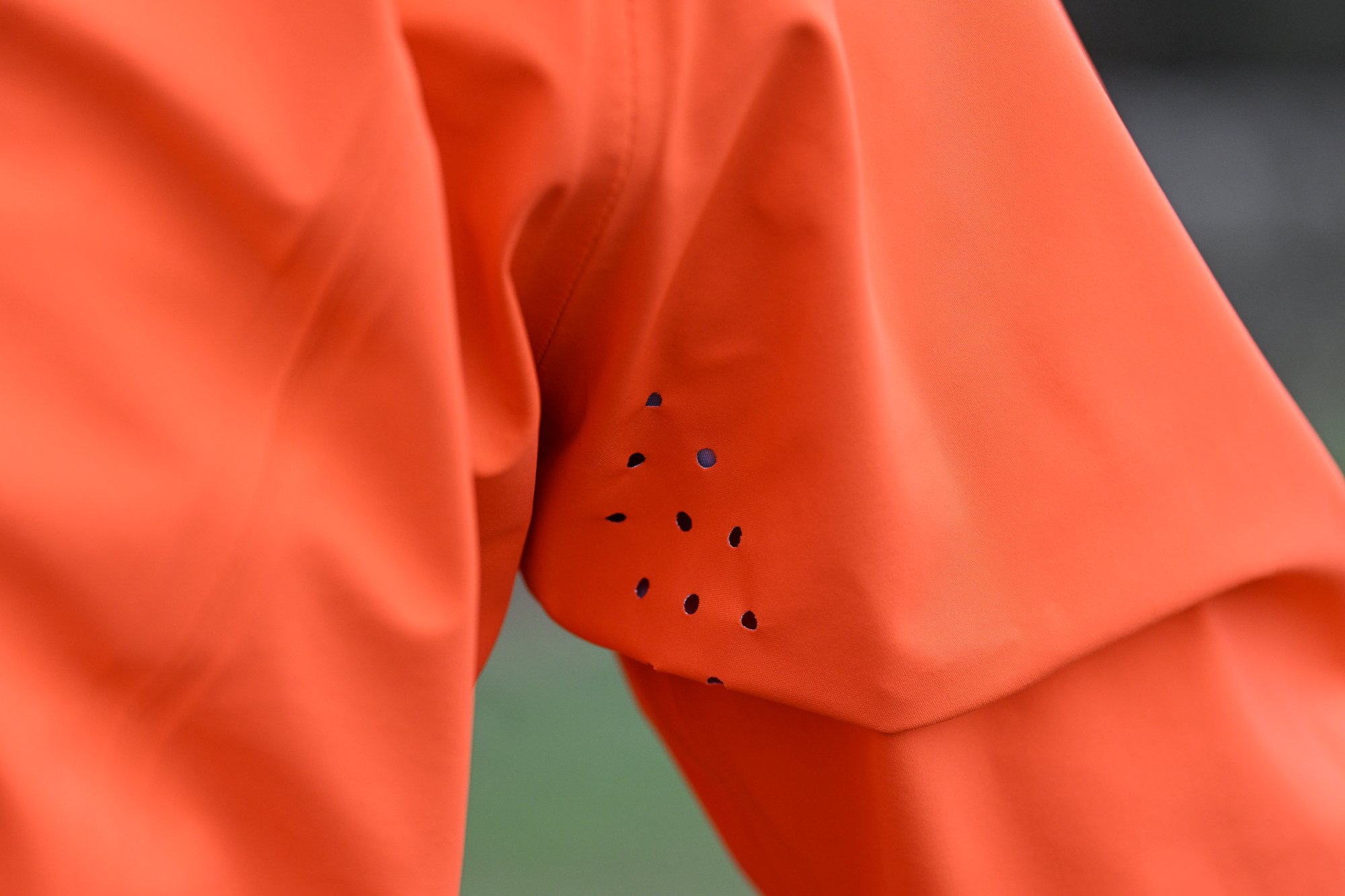 Close up of the perforations under the arm of an orange jacket