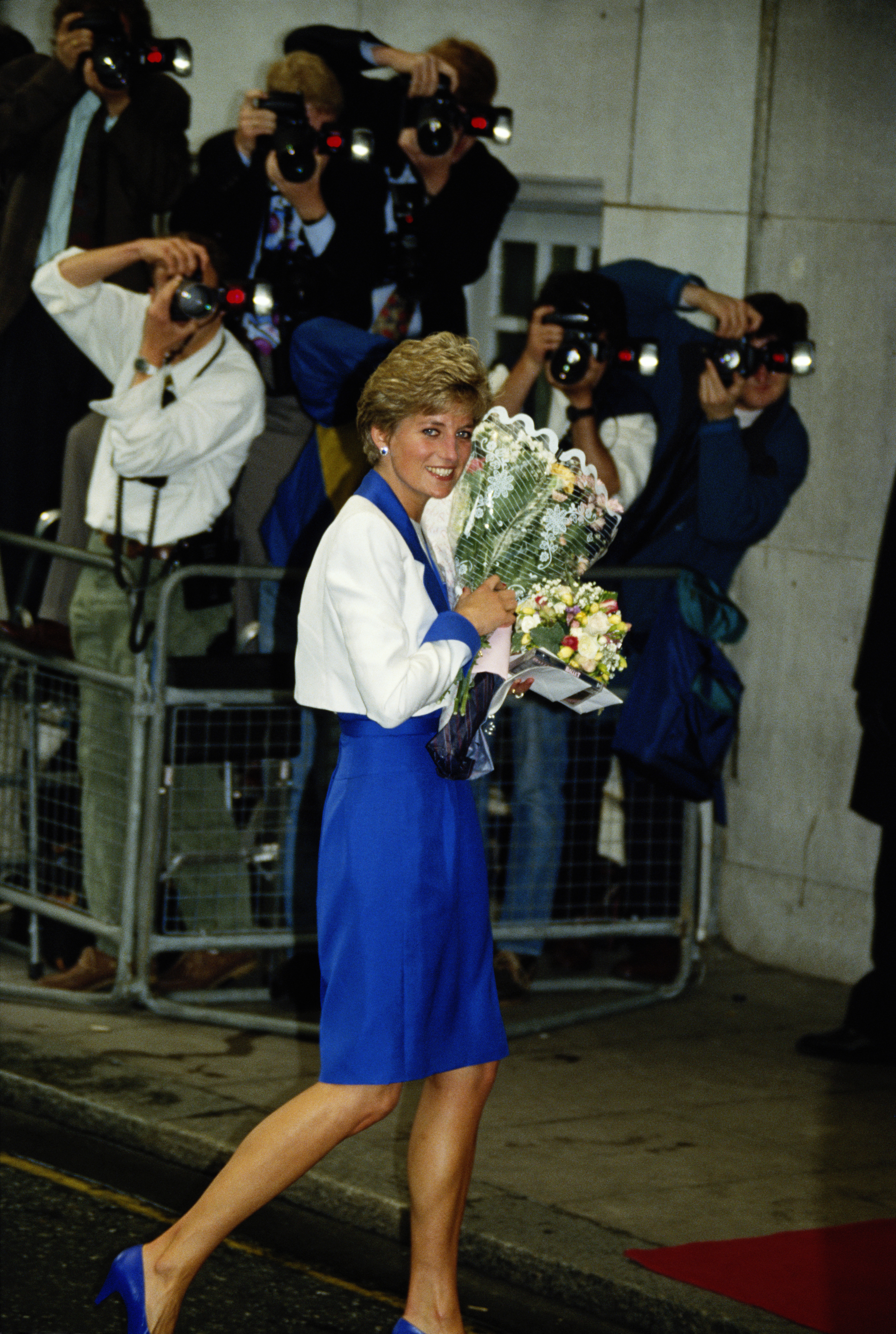 Princess Diana carrying flowers wearing a blue dress and white jacket