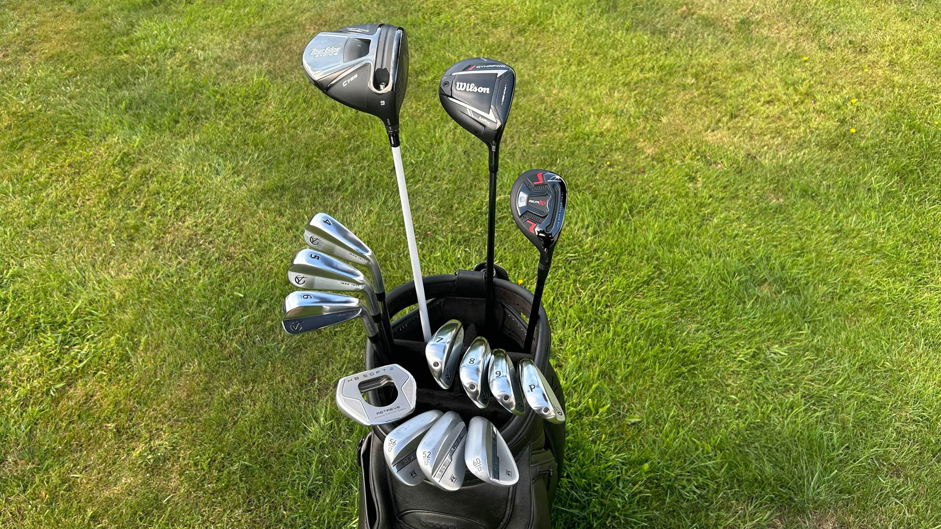 a bag of 14 golf clubs with a grassy background 