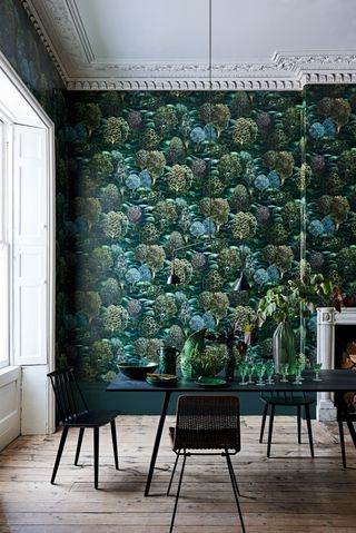 Forest wallpaper by Cole & Son in a dining room with dark chairs and table