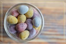 a close up of Mini Eggs in a glass bowl on a wood sideboard
