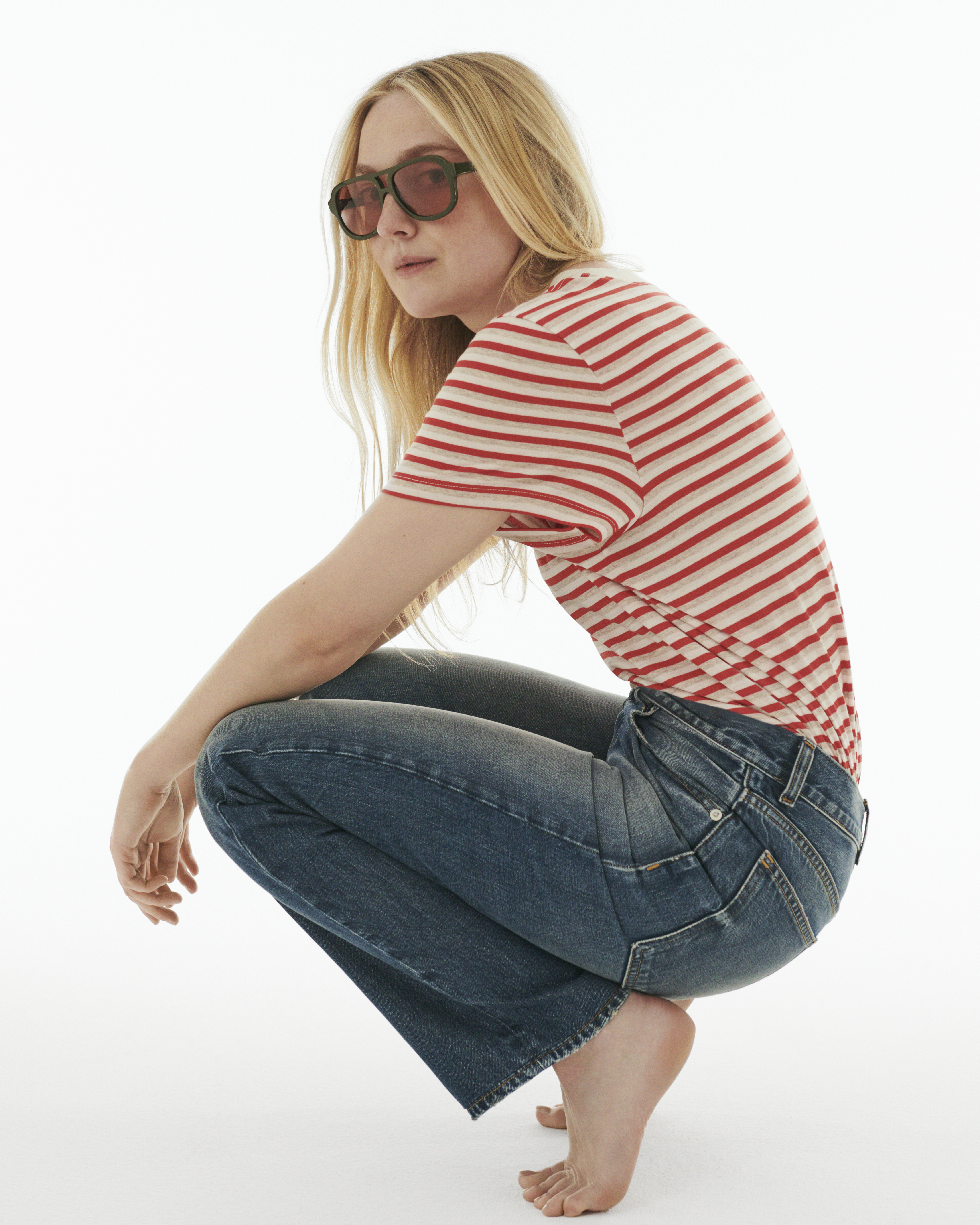 Dakota Fanning for Madewell campaign wearing The Dakota Perfect Crewneck Tee in red stripe and The Dakota Longline Straight Jean and sunglasses on white background