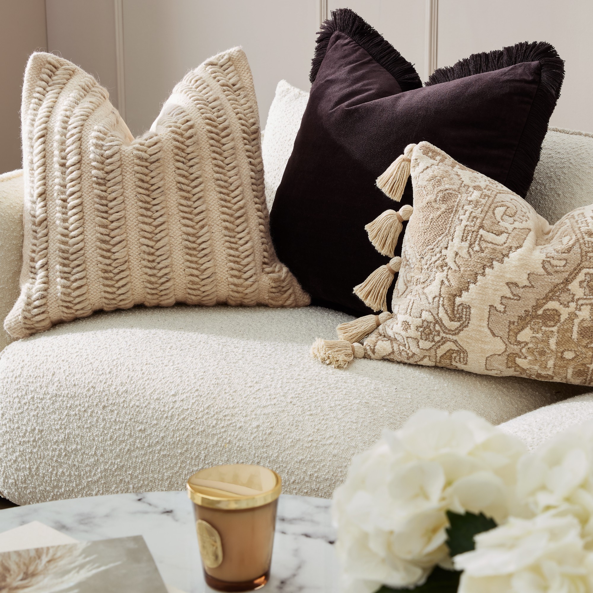 A living room with a cream boucle sofa and textured cushions from the Primark The Edit homeware collection