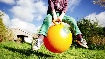 kid bouncing on yellow ball