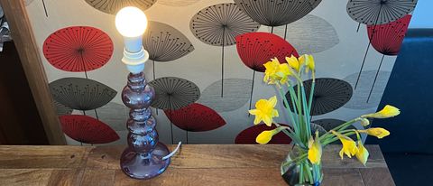 The Innr Smart Bulb Color in a lamp next to a bunch of daffodils