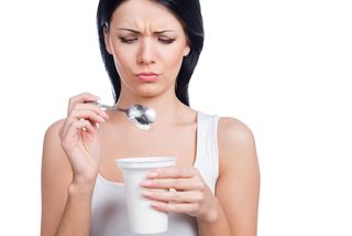 A woman looks at her yogurt cup.