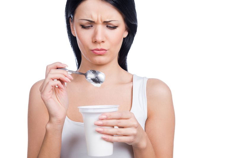 A woman looks at her yogurt cup.