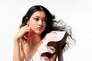 Model in pink dress wearing Valentino Beauty makeup and holding Valentino Beauty compact