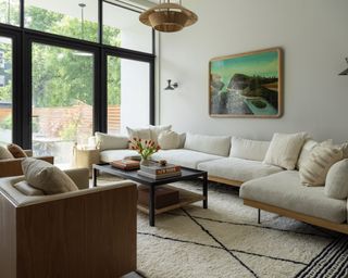 sofa arranging mistakes, neutral living room with large sectional, large rug, two armchairs, pendant, artwork, crittall doors, view of garden