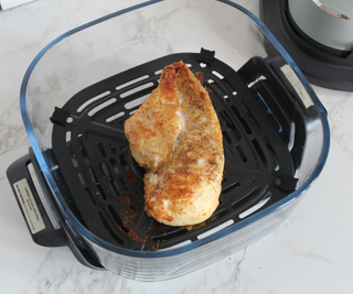 A golden, roast chicken fillet in the Ninja Crispi Portable Glass Air Fryer