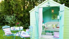 garden area with blue wooden shed and table and chairs