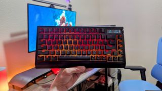 The Razer BlackWidow V4 Pro 75% held up by a hand with orange and yellow lighting.