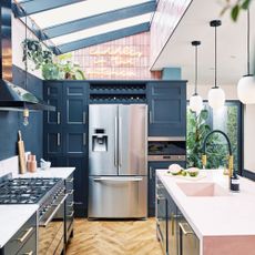 navy blue kitchen with island, large american style fridge, pendant lights and sky lights