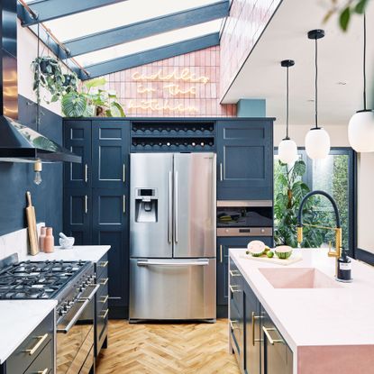 navy blue kitchen with island, large american style fridge, pendant lights and sky lights