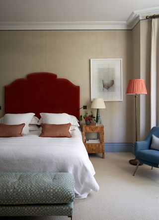 neutral bedroom with red headboard and floor lamp