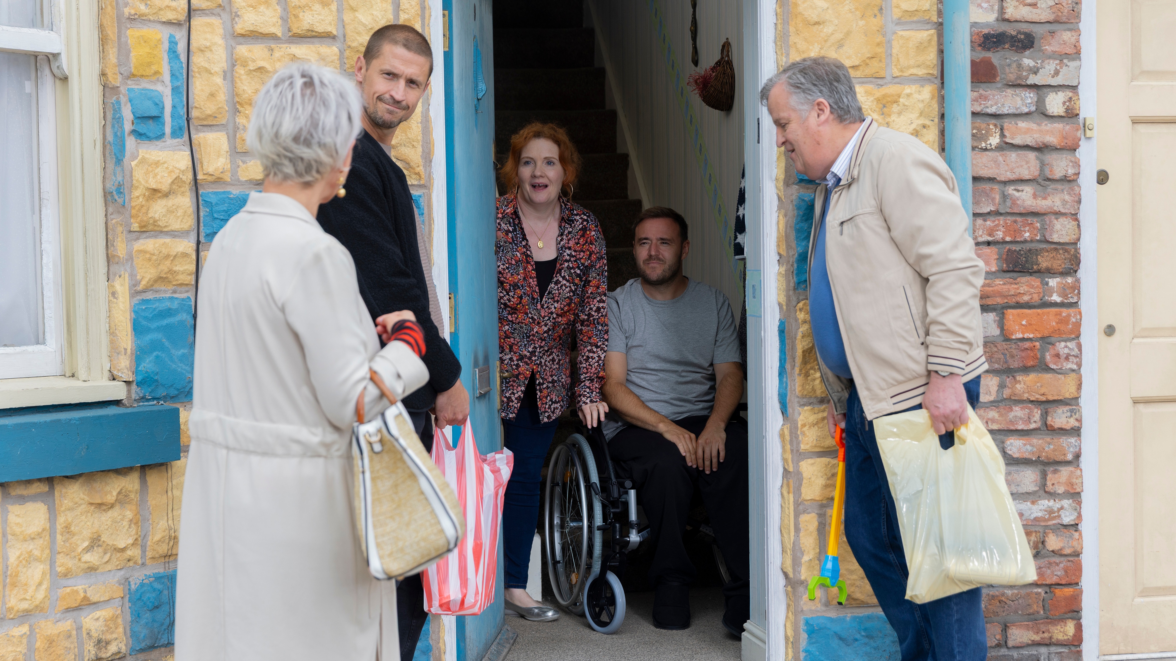 Tyrone in a wheelchair at the door of his house with Fiz