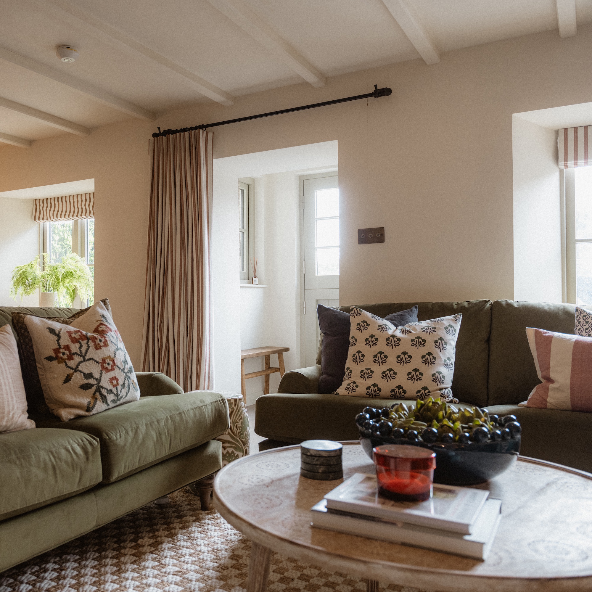 view of cottage sitting room with green sofas and circular wooden coffee table