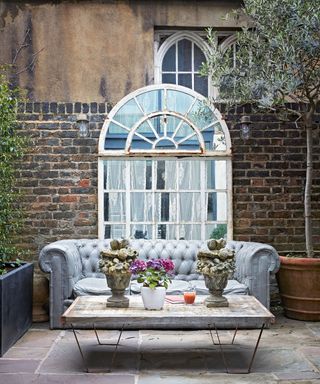 courtyard garden with sofa, low table with ornaments and mirror