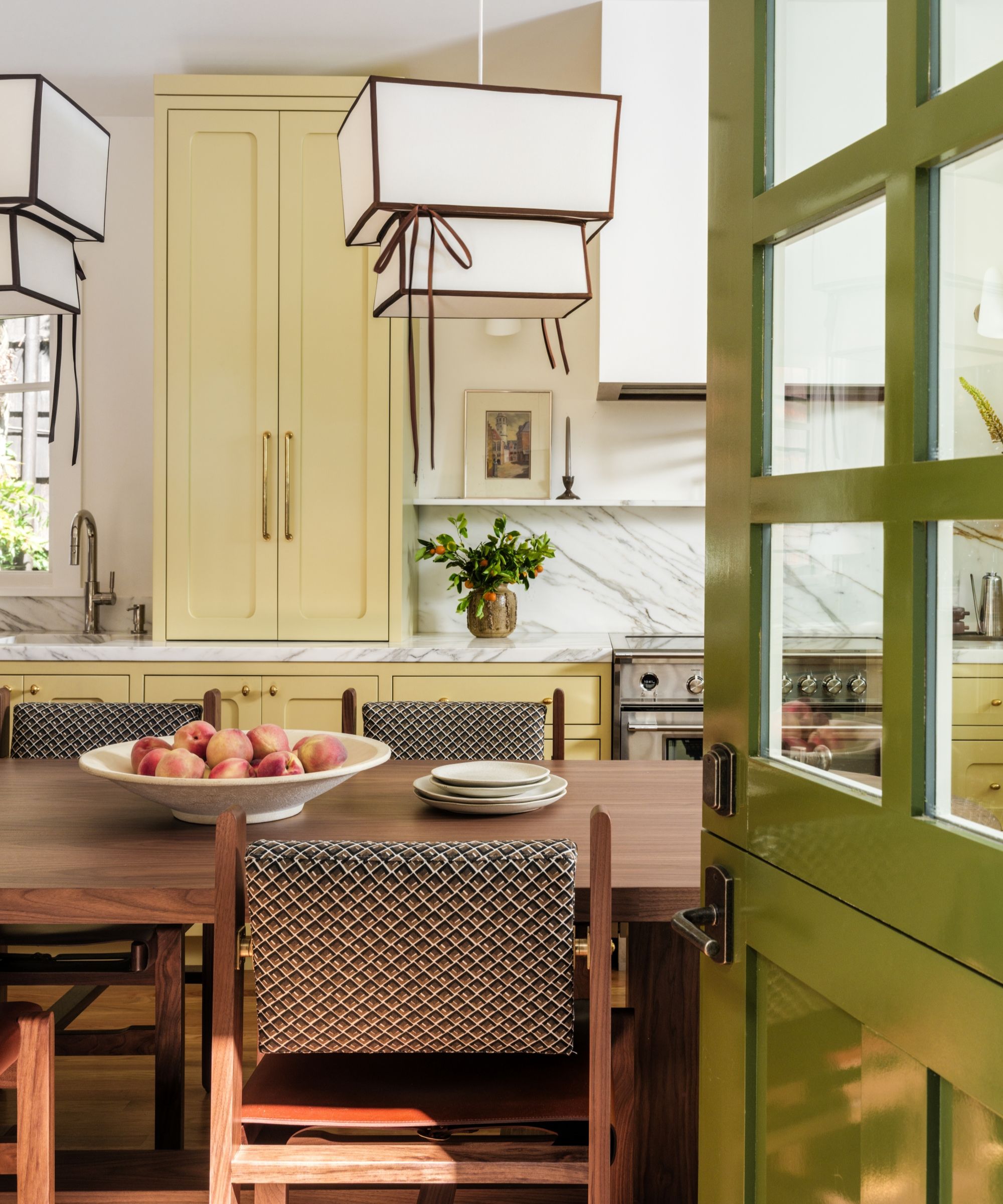 A yellow kitchen with marble countertops, a wooden table, and a green Dutch door
