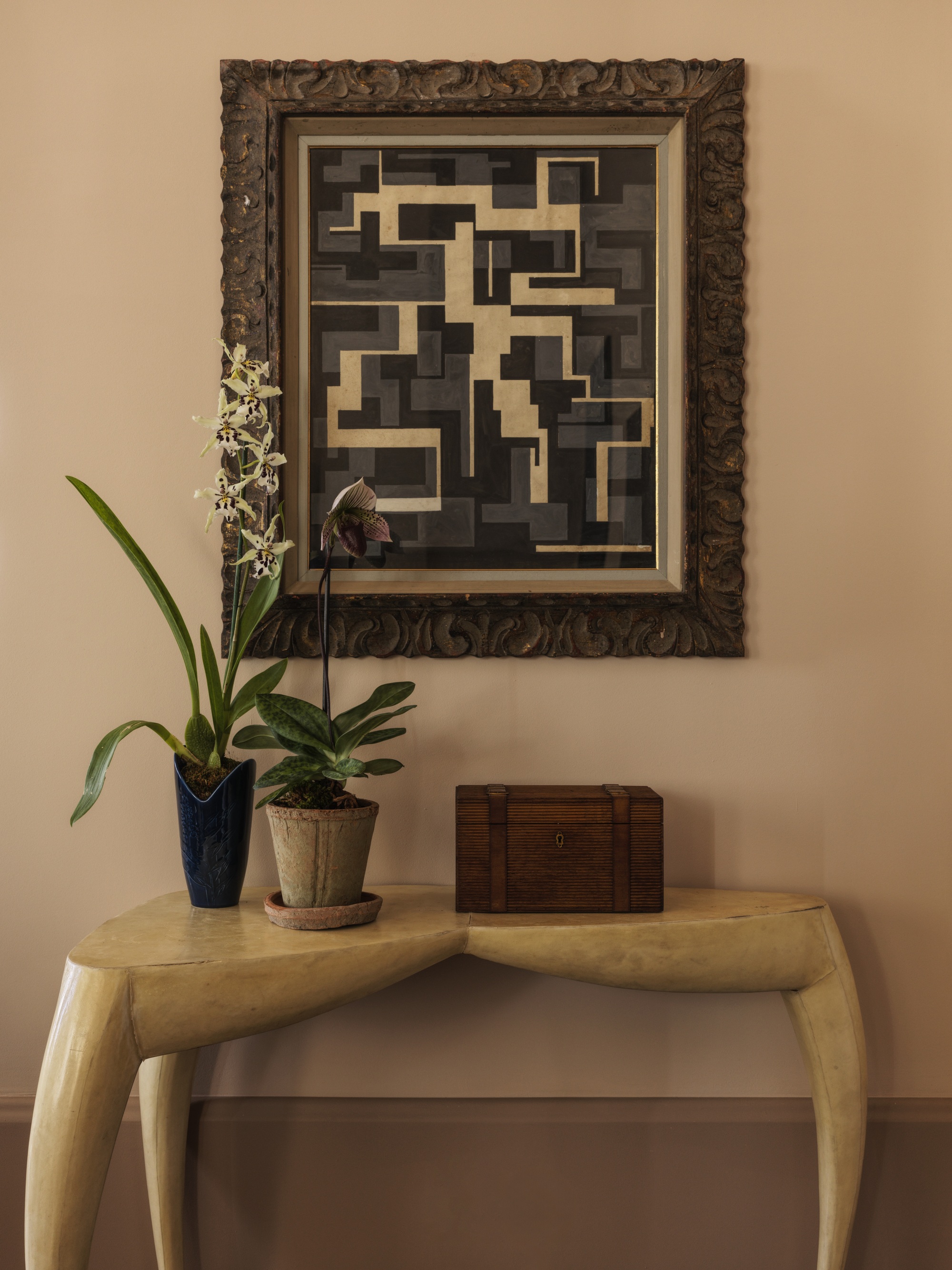 console table with artwork hanging, and styled with potted orchids and a box