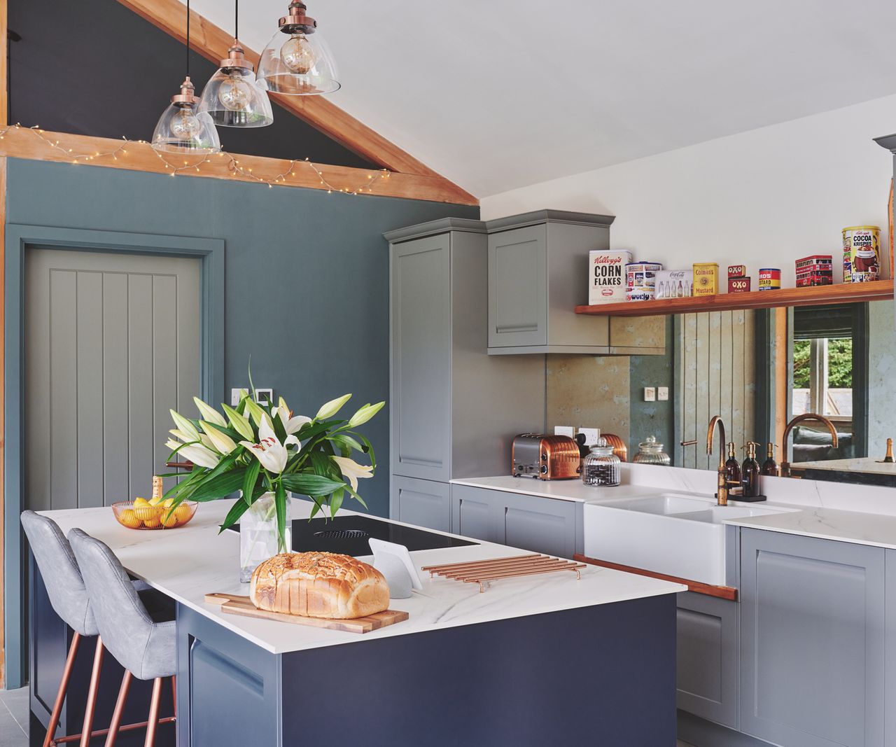 A classic open-plan kitchen with Shaker-style units, large kitchen island and three pendant lights