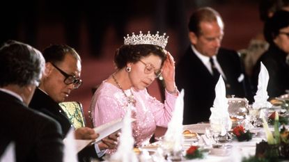 peking, china october 13 the queen adjusting her tiara whilst reading the menu before dinner is served at a banquet held in her honour during her visit with prince philip to peking, china the queen is wearing queen marys girls of great britain and ireland tiara photo by tim graham photo library via getty images