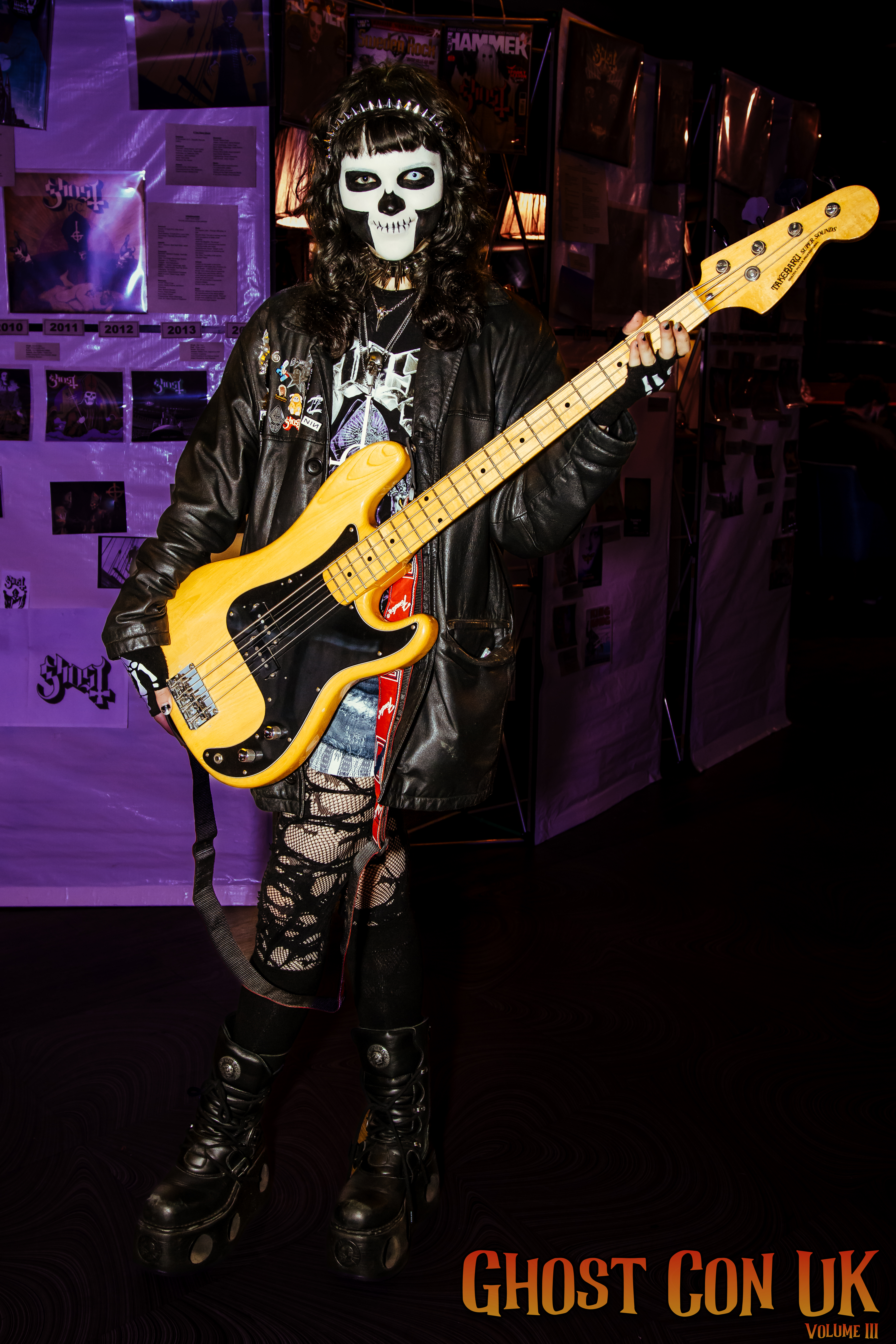 A fan in Papa facepaint with a bass guitar