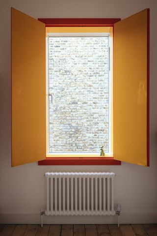 Window with yellow and read shutters above white radiator.