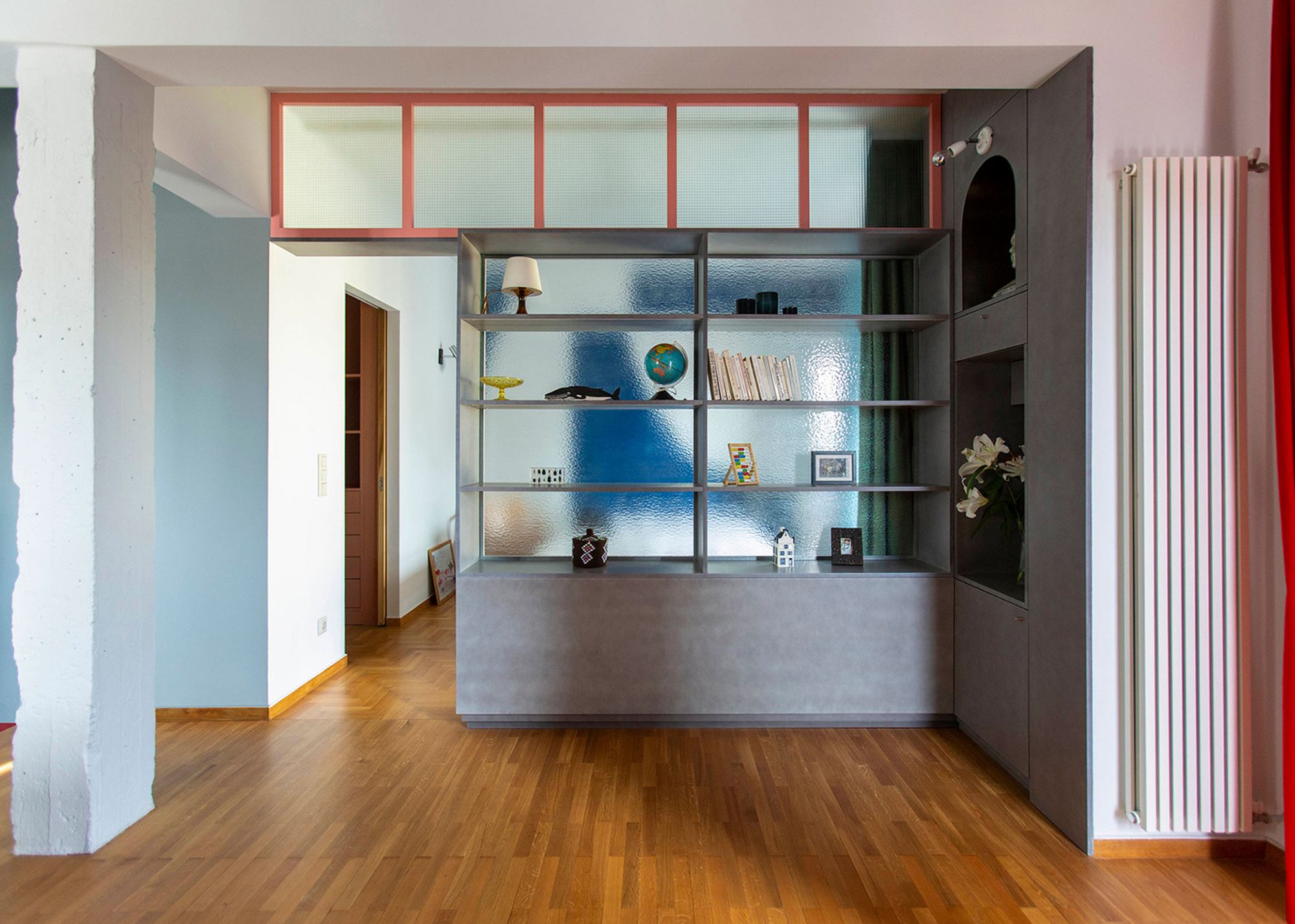 a room divider with storage with clear backing filled with decorative items in an open living area