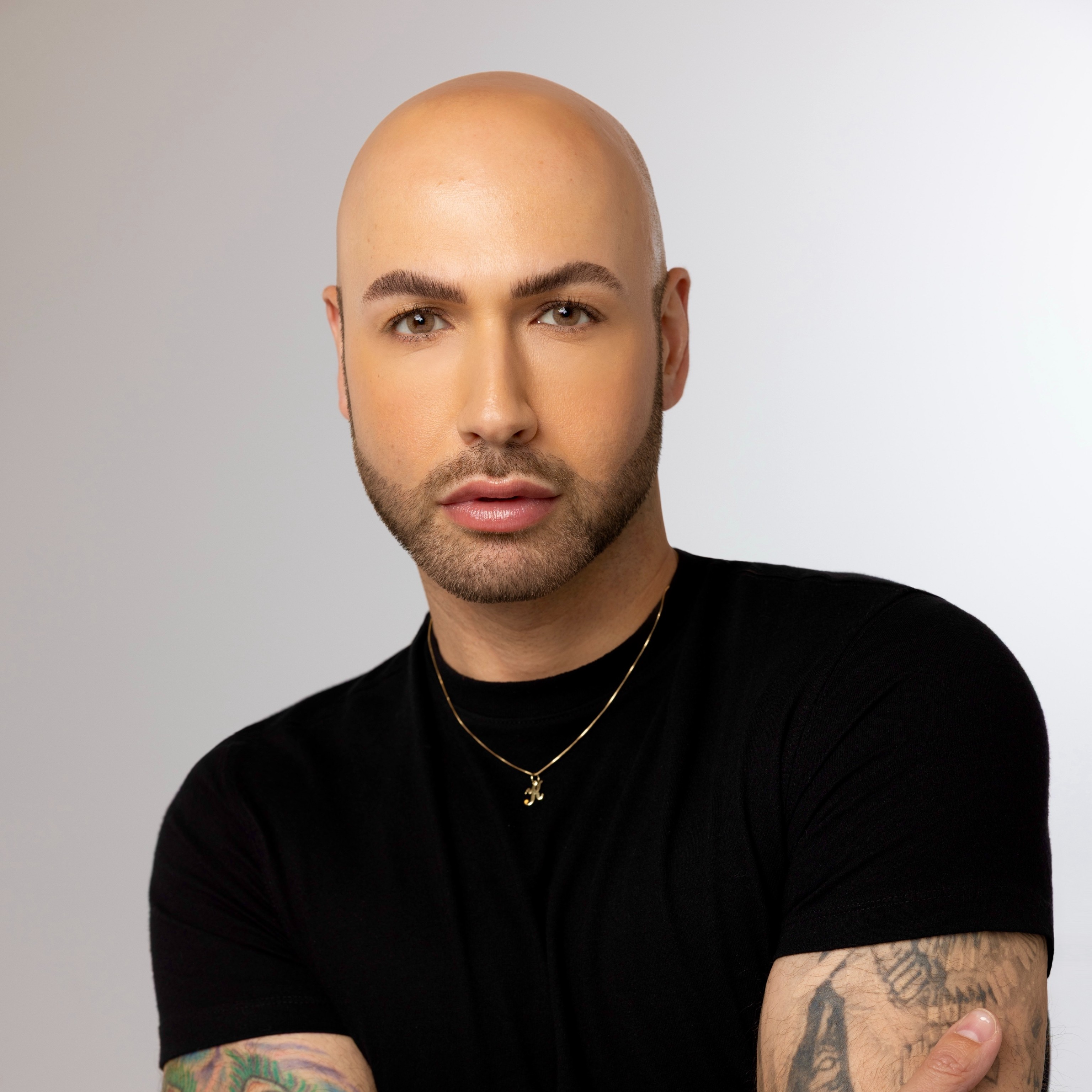 Steve Kassajikian poses for a headshot in front of a white background wearing a black t-shirt.