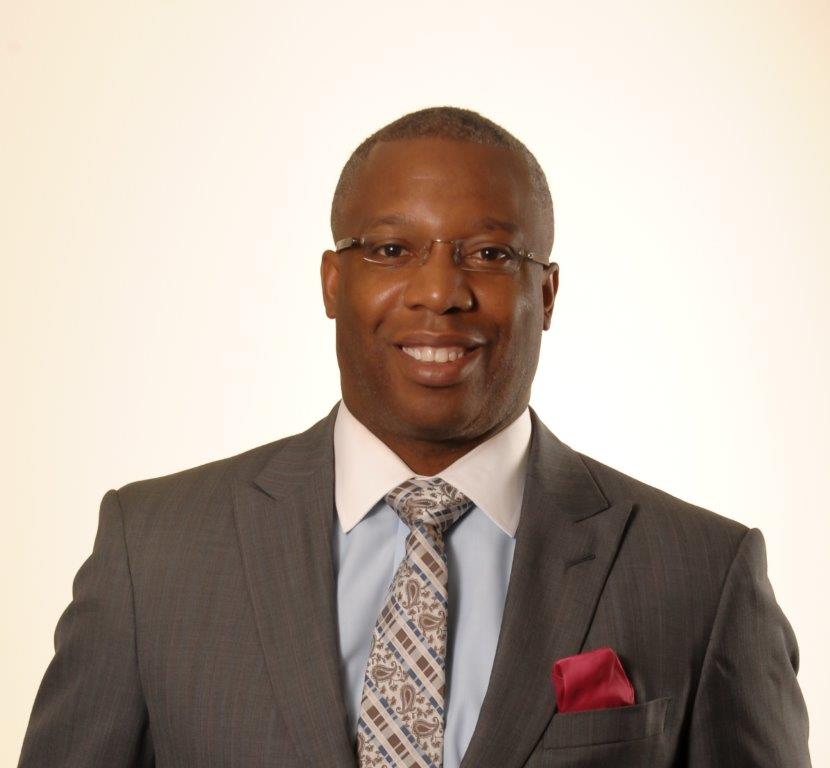 Dr. Anthony Brissett in a gray suit and colorful tie with glasses