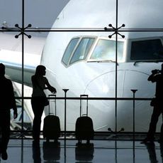 people standing an airport with a plane outside the window