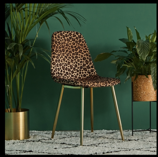 Velvet chair leopard print in front of a green background planters with plants