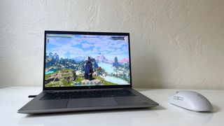 The HP ZBook Firefly 14 G11 running Enshrouded (Keen Games) next to a gray mouse on a white table