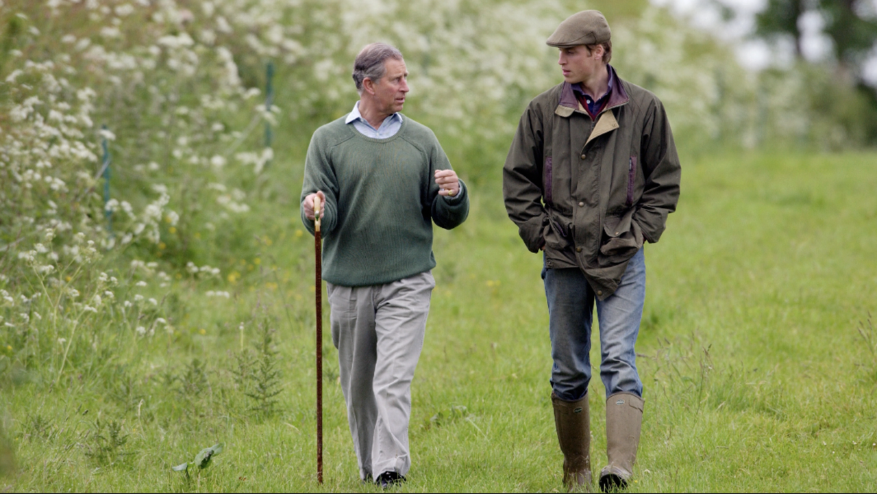 Prince William, In Countryman Outfit Of Tweed Cap And Waxed Jacket And With His Hands In His Pockets, Visits Duchy Home Farm With Prince Charles Who Is Holding A Shepherd&#039;s Crook Walking Stick