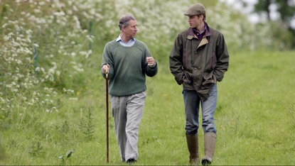Prince William, In Countryman Outfit Of Tweed Cap And Waxed Jacket And With His Hands In His Pockets, Visits Duchy Home Farm With Prince Charles Who Is Holding A Shepherd's Crook Walking Stick