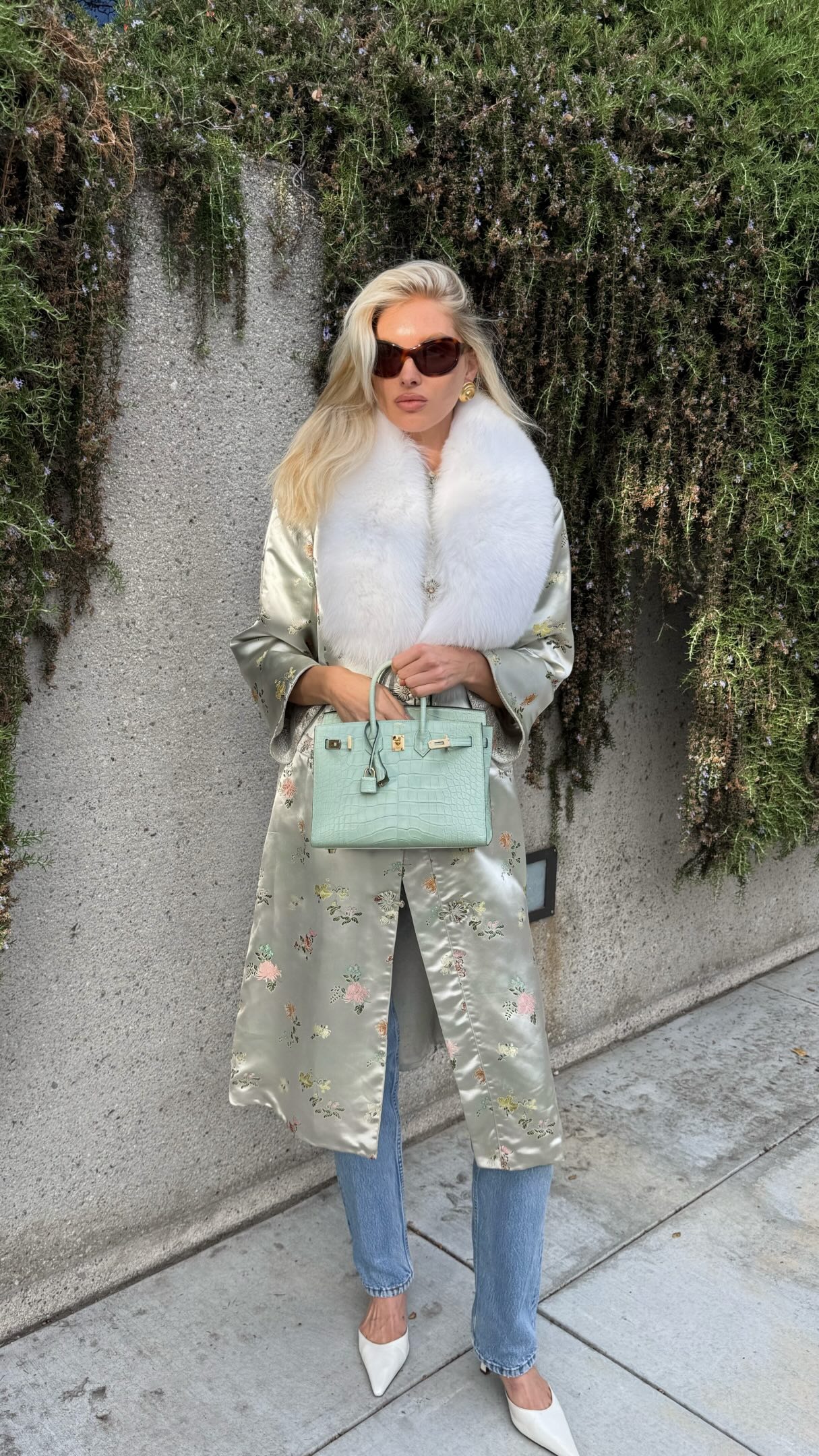 Model Elsa Hosk wears a fur-trimmed ornate knee-length jacket wth stovepipe jeans and white pointed-toe heels.
