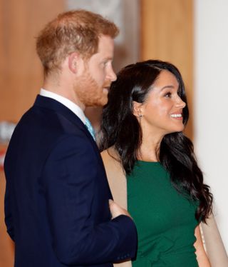 Side profile shot of Prince Harry and Meghan Markle in green