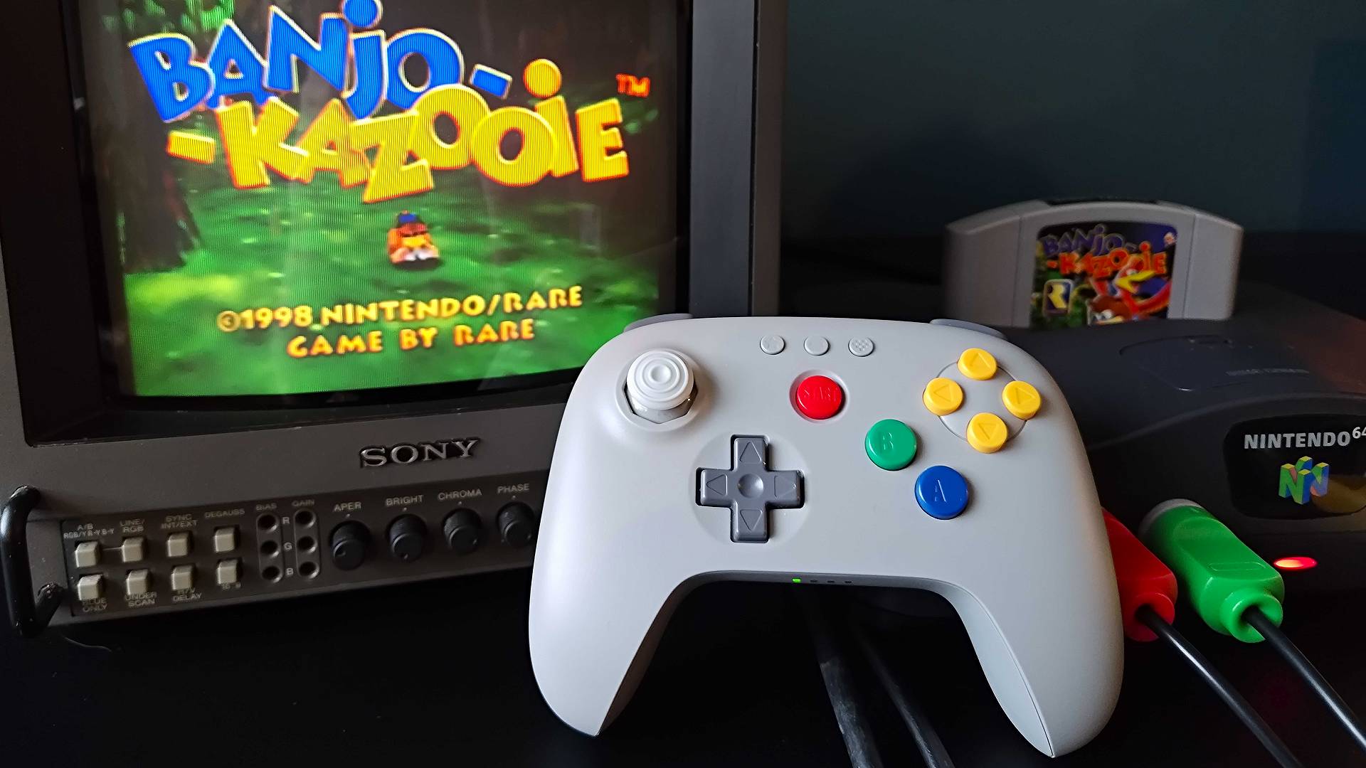 8Bitdo N64 controller leaning against original N64 connected to Sony PVM CRT TV with Banjo Kazooie title screen on display.