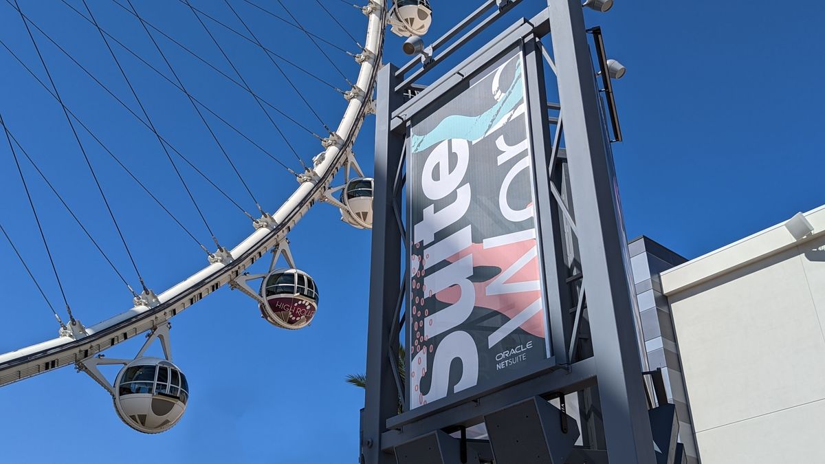 A SuiteWorld sign at Oracle NetSuite&#039;s conference, with a ferris wheel and blue sky in the background.