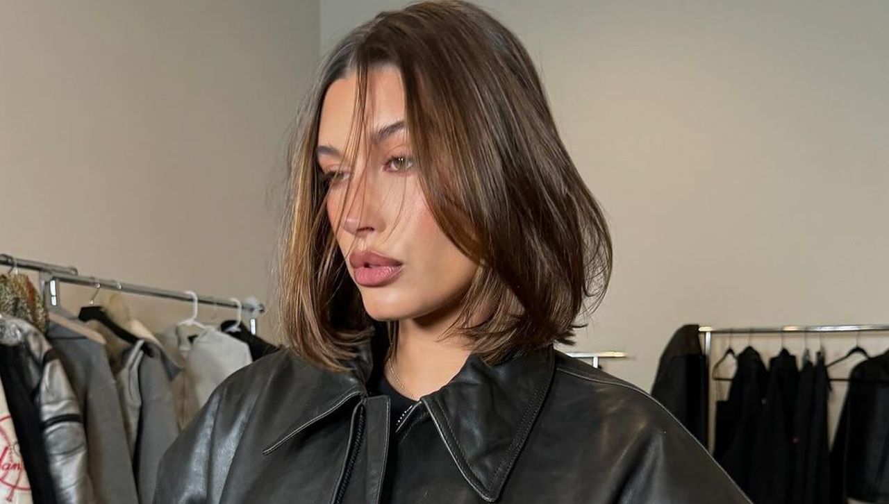 Hailey Bieber stands in a wardrobe studio wearing a leather jacket and a fresh bob haircut